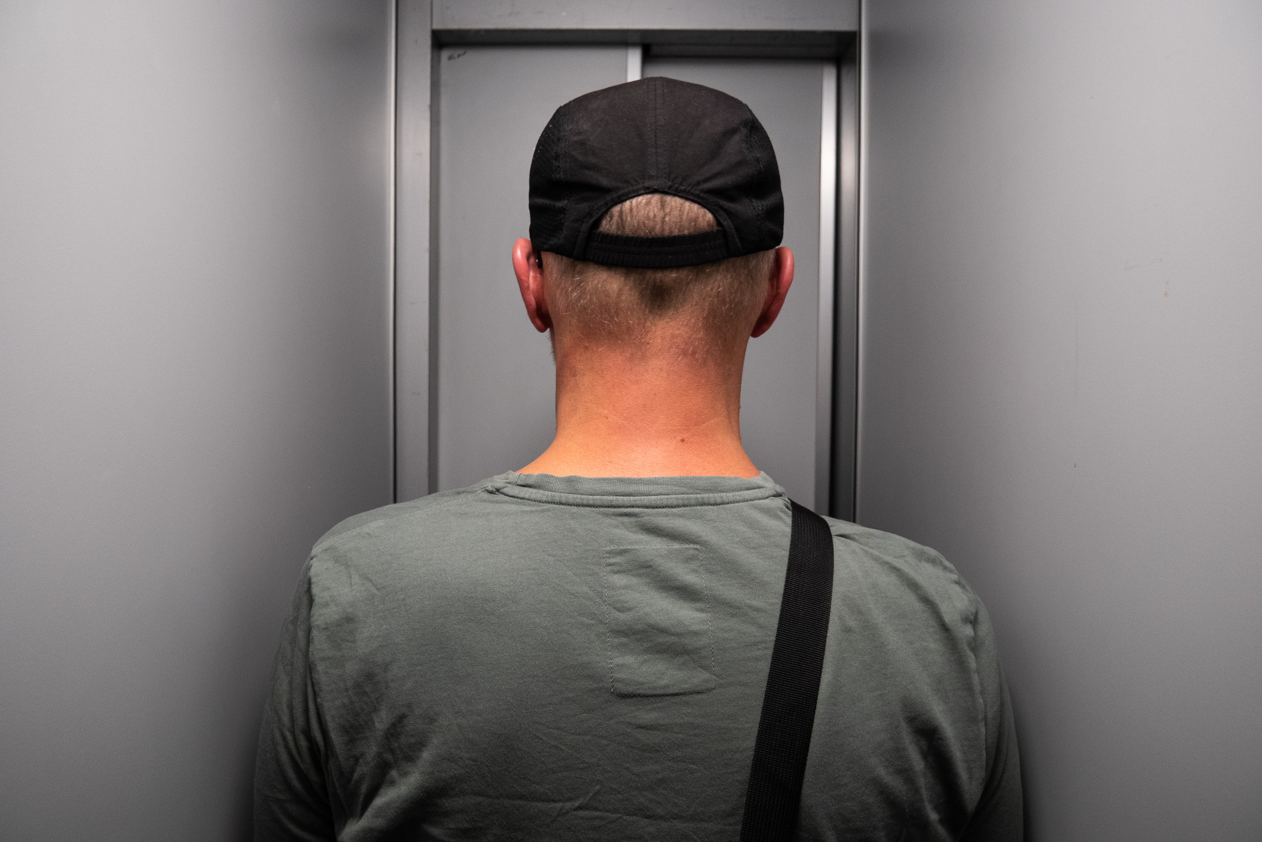Im Aufzug – Rückenansicht mit Kappe